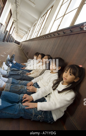 Elementary school boy sitting on library floor reading Stock Photo - Alamy