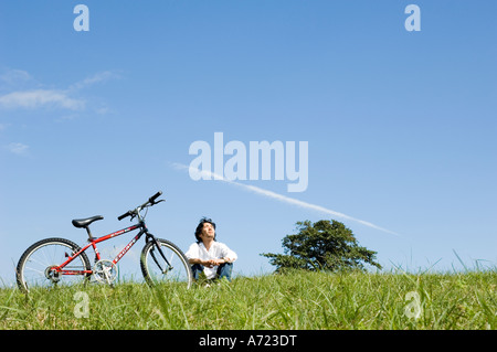 Young man sitting next to bicycle Stock Photo
