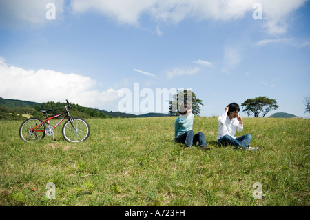 Young couple sitting on field, man using mobile phone Stock Photo