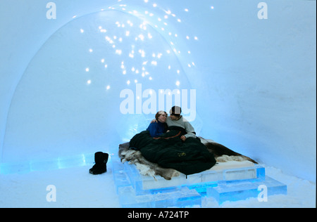 A couple relax in a sleeping bag on a bed of raindeer skins in their room at the Ice Hotel Sweden Stock Photo