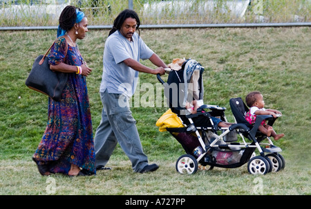 African American couple pushing double stroller along soccer field. Carondelet Field by Expo School St Paul Minnesota USA Stock Photo