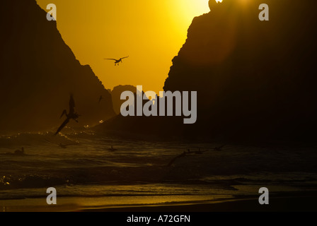 Zipolite - sunset with godwit and men in the background stand on the rocks - Oaxaca - Mexico Stock Photo