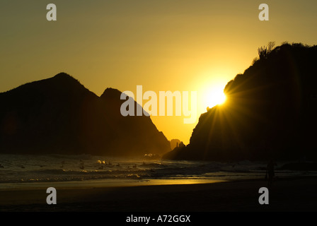 Zipolite - sunset with godwit and men in the background stand on the rocks - Oaxaca - Mexico Stock Photo