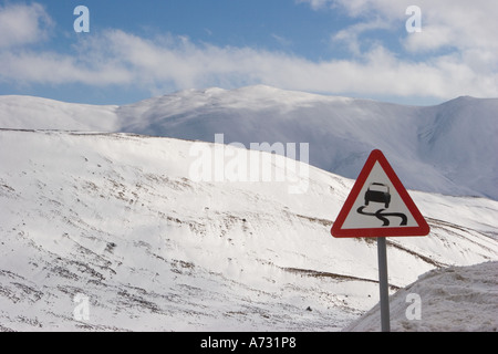 Warning A93 road sign danger Ice Risk of Skidding  Winter snow landscape at Spittal of Glen Shee, Braemar, Cairngorms, National Park Scotland UK  Stock Photo