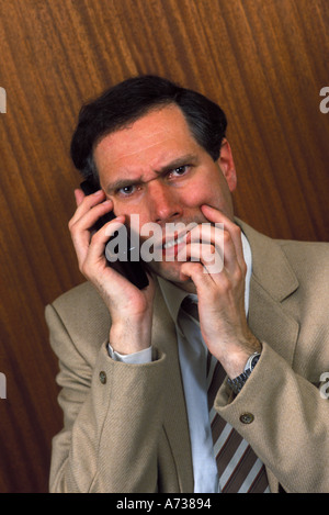 businessman on mobile phone looking under pressure Stock Photo