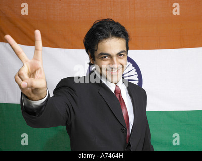 VDA 201918 South Asian Indian executive showing victory sign standing in front of flag of india in background MR 702A Stock Photo