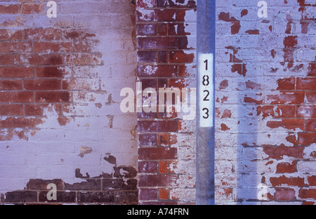 Part of a numbered silver lamp post in front of an alcoved brick wall on which most of paint covering has weathered away Stock Photo