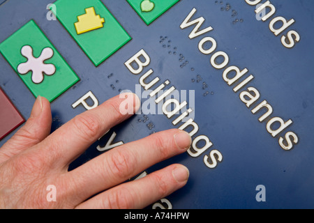 Hand reading braille on public information sign St Fagans Wales UK Stock Photo