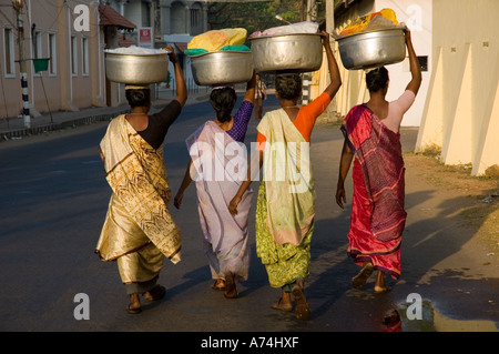 Women walking along a street with bowls balanced on their heads in Cochin Kerala South India Stock Photo