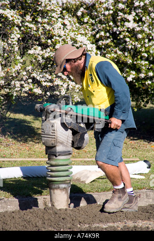 a worker using a compacting machine to flatten roadfill Stock Photo