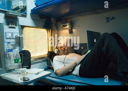 A man using a laptop computer on an air-conditioned Indian train Stock Photo