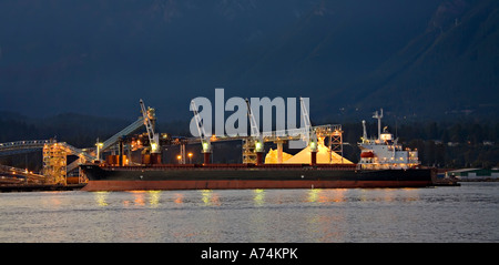 Ship and cranes at industrial wharf with sulphur pile Vancouver Canada Stock Photo