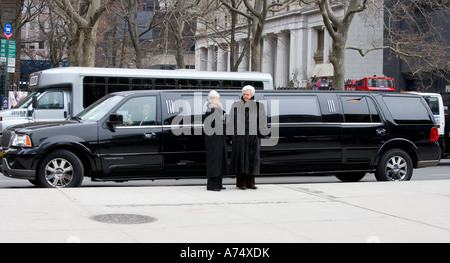 two ladies in fur coats with stretch limo engaged in conversation Stock Photo