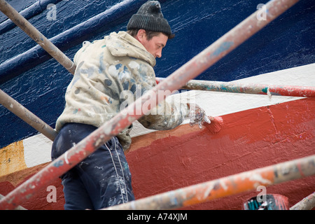 Workmen Boat painting. Ships, nautical, transport, fishing, wooden, painter at MacDuff ship & fishing boat repair yard north-east Scotland UK Stock Photo