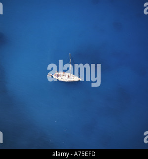 View overhead down on stationary white yacht on a deep blue sea in cove of Shipwreck Bay on Zakynthos Island The Greek Islands Stock Photo