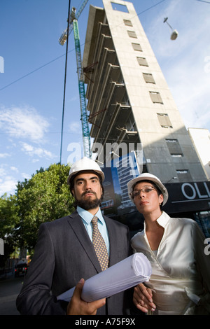 Businesspeople carrying blueprints in construction area Stock Photo