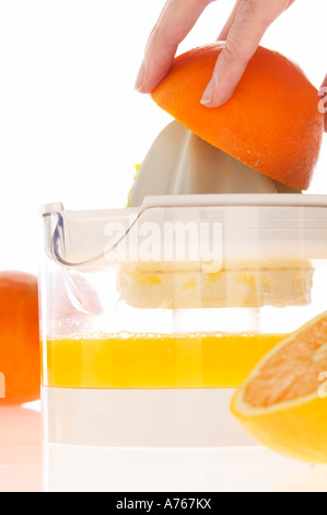 Woman preparing orange juice on juicer, close-up Stock Photo