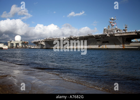 USS Abraham Lincoln is towed into Pearl Harbor and approaches the Sea Based X-band Radar undergoing service. Stock Photo