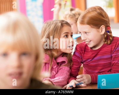 Girls (4-7) whispering in classroom Stock Photo