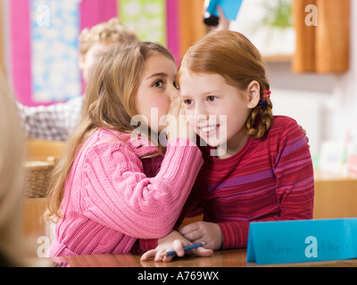 Girls (4-7) whispering in classroom Stock Photo