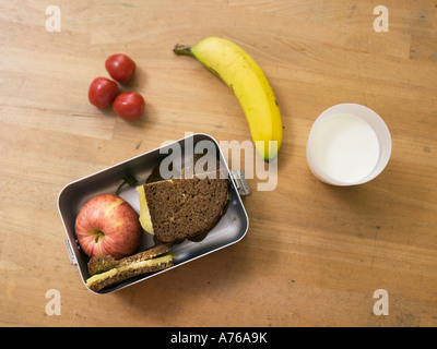 Lunch box on table, with sandwich, fruits and glass of milk, elevated view Stock Photo