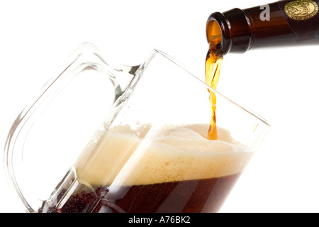 Pint of dark beer being poured into glass on a pure white background. Stock Photo