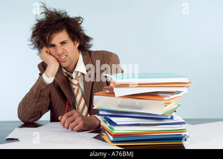 Businessman sitting on desk with stack of file, head in hands, portrait Stock Photo