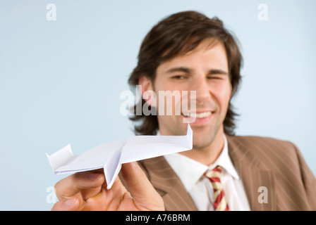 Businessman holding paper plane, winking, smiling, close-up Stock Photo
