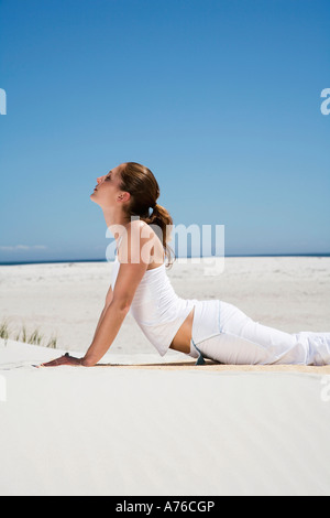 Young woman exercising yoga on beach Stock Photo