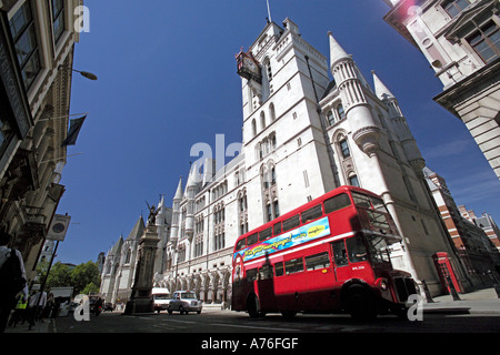 Low wide angle of a traditional red double decker route master bus passing the Royal Courts of Justice aka Law Courts in London. Stock Photo