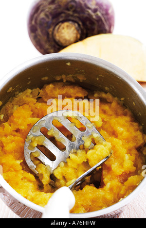 Mashed rutabaga vegetables and masher in pot, elevated view Stock Photo