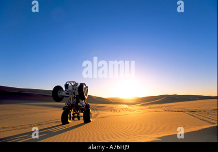 A Quad biker performing freestyle jumps on the sand dunes of the Namibian desert at sunset. Stock Photo