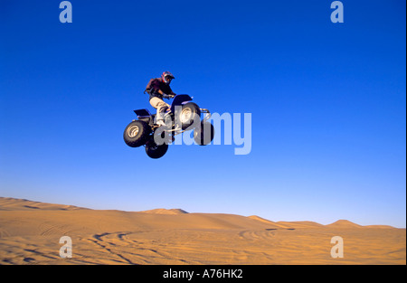 A Quad biker performing freestyle jumps on the sand dunes of the Namibian desert. Stock Photo