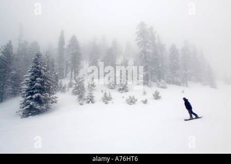 Wide angle of a lone snowboarder on a fog bound slope at the Heavenly Ski Resort in Lake Tahoe. Stock Photo