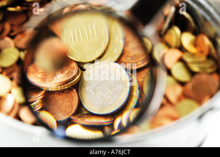 Pot of euro coins under magnifying glass, close-up Stock Photo