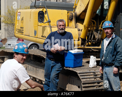 Construction workers take a break for lunch from trenching sewer lines with their backhoe Stock Photo