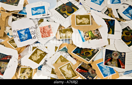 Pile of used franked British postage stamps torn from envelopes for collection Stock Photo
