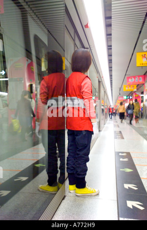 Reflection of MTR platform assistant on glass panels of  platform. Stock Photo