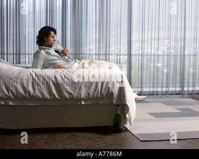 Man reclining on bed sipping champagne in bedroom Stock Photo