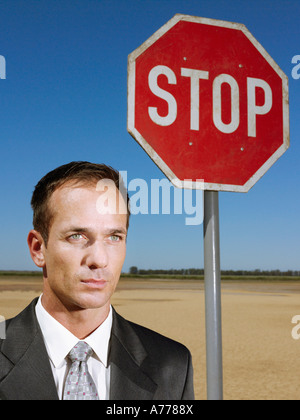 Businessman standing next to stop sign in desert, head and shoulders Stock Photo