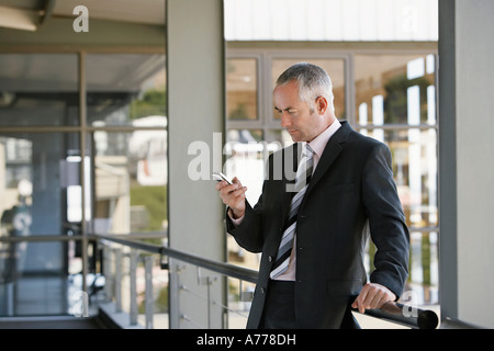 Businessman leaning on railing, using mobile phone. Stock Photo