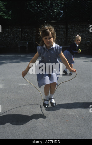 Schoolgirl skipping in school playground Stock Photo