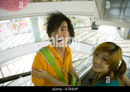 Teenage couple riding escalator in mall, high angle view Stock Photo