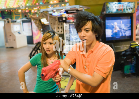 Teenage couple playing game in video arcade
