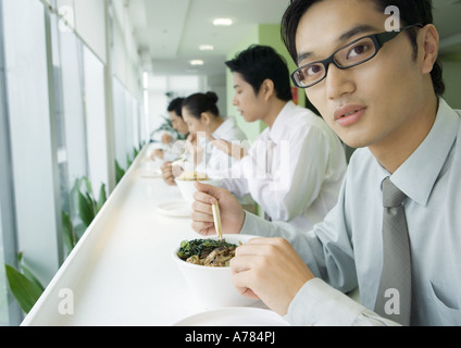 Businessman having lunch in cafeteria, looking at camera Stock Photo