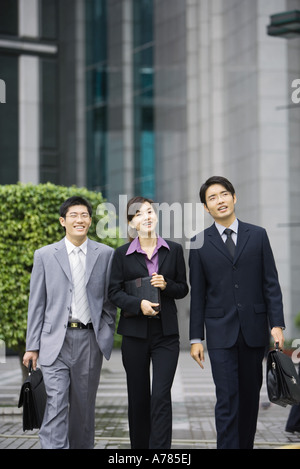 Three young executives walking side by side Stock Photo