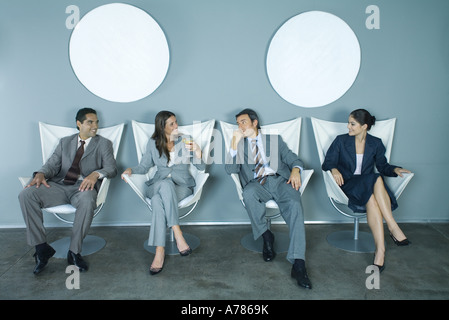 Four business executives sitting side by side Stock Photo