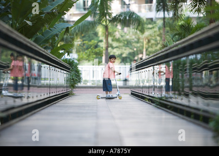 Boy riding scooter, in mid distance Stock Photo