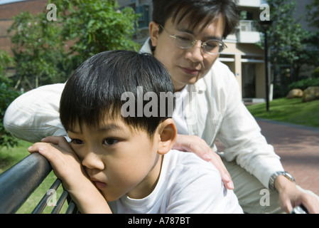 Father and son on bench, boy pouting Stock Photo