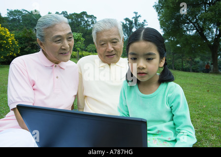 Girl and grandparents using laptop Stock Photo